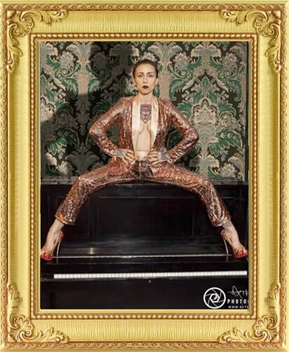 cabaret performer, cabaret dancer from our entertainment agency London in a gold suit sits on a piano