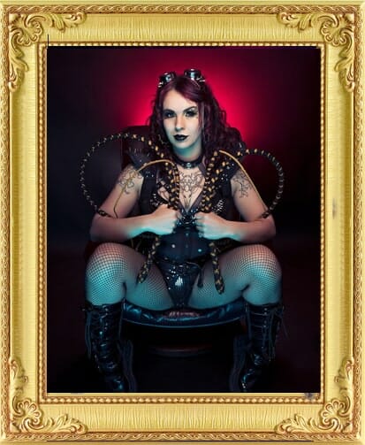 whip act cabaret performer from our entertainment agency Brighton with devil horns seated in a chair